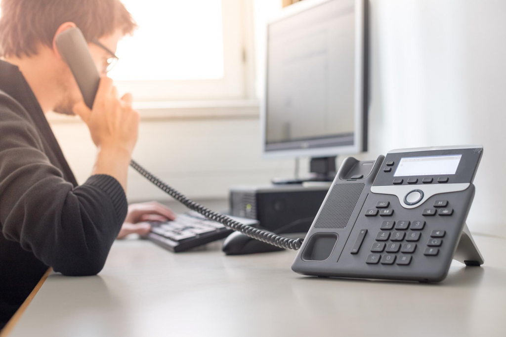 homem ao telefone realizando um atendimento ao cliente para simbolizar o contéudo desse artigo que é Como Aumentar a Eficiência do Atendimento ao Cliente com Telecomunicações