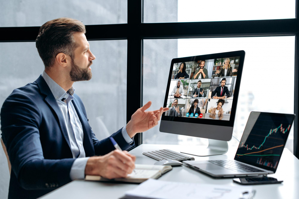 Empreendedor conduzindo uma reunião de negócios por videoconferência, exemplificando comunicação unificada em ação, com a tela mostrando diversos colaboradores remotos, simbolizando a colaboração e produtividade elevada possibilitadas por sistemas UC integrados em um ambiente corporativo moderno.